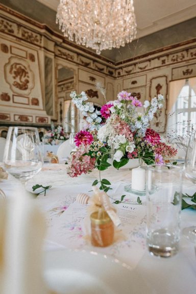 Blumenschmuck und festlich gedeckter Tisch in eleganter, gut beleuchteter Umgebung.